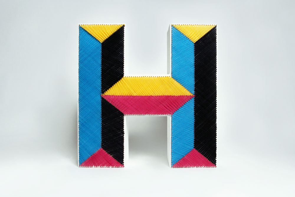 A tactile piece of typography of the letter H created from wool