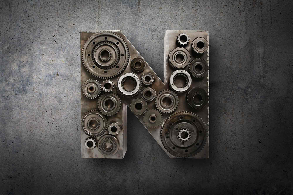 A tactile piece of typography of the letter N created from steel and cogs